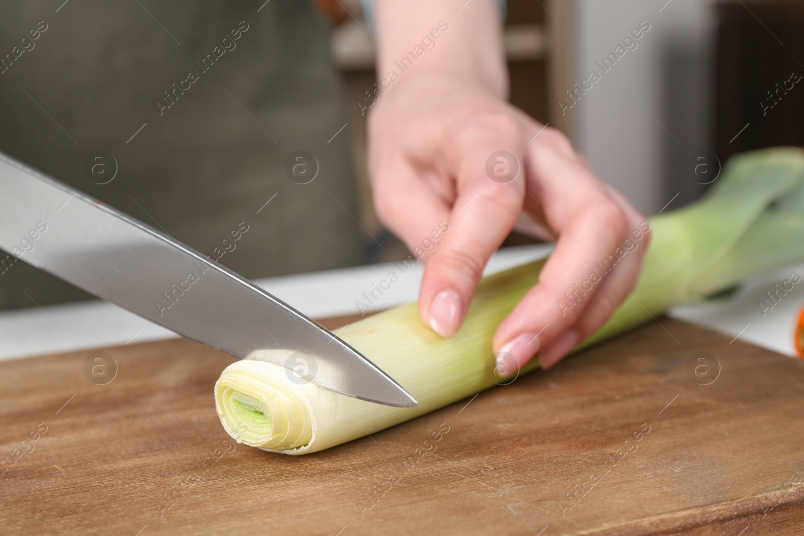 Photo of Healthy food. Woman cutting leek at table, closeup