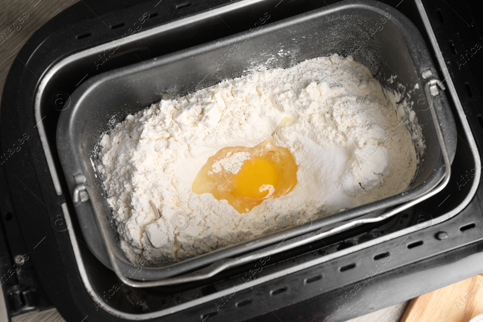 Photo of Making dough. Flour and egg in breadmaker pan, above view