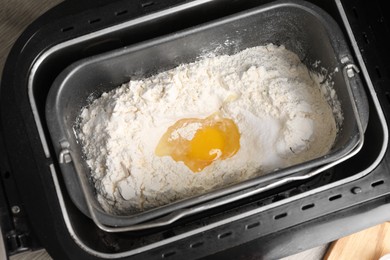 Making dough. Flour and egg in breadmaker pan, above view