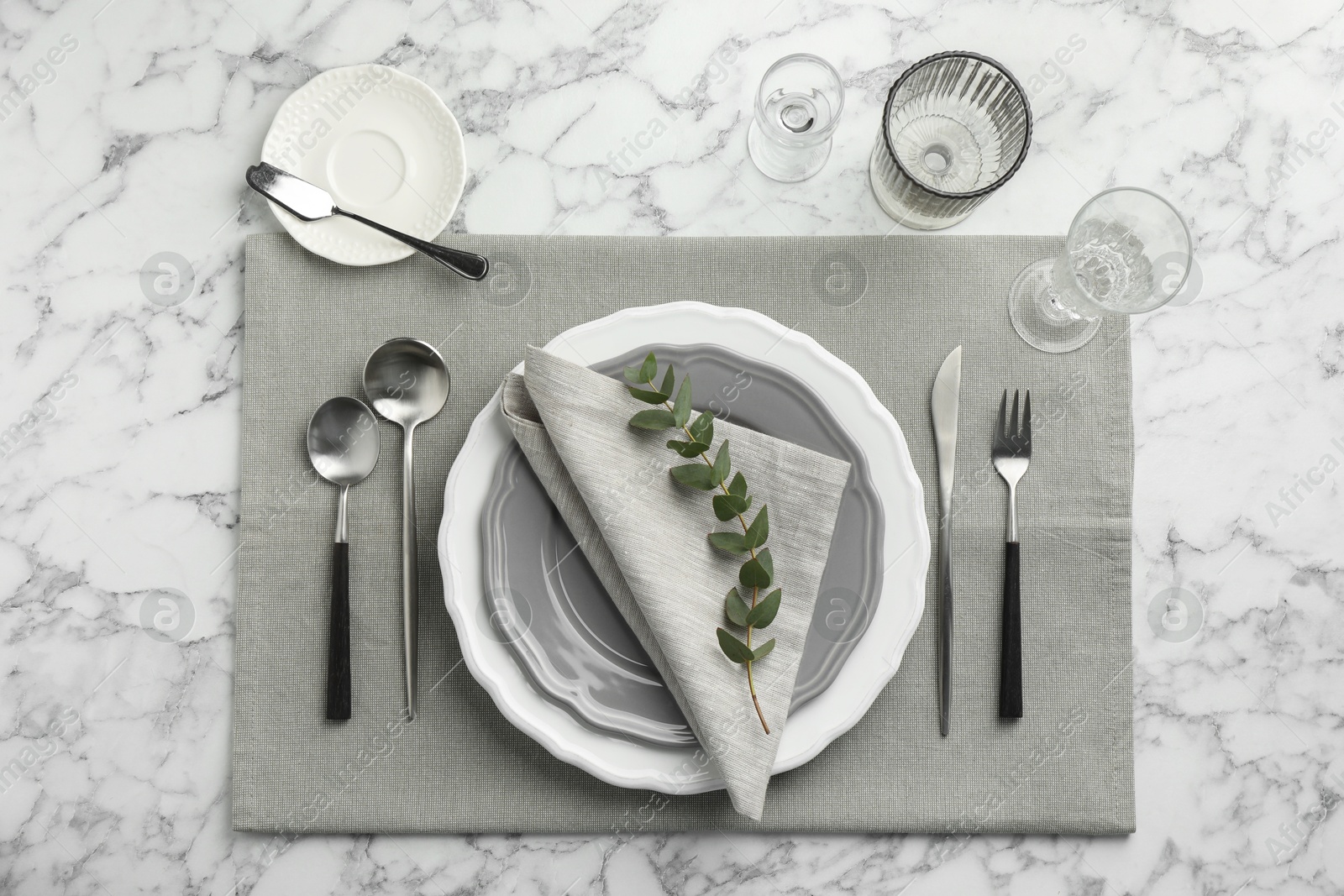 Photo of Stylish setting with cutlery, glasses and plates on white marble table, flat lay