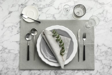 Stylish setting with cutlery, glasses and plates on white marble table, flat lay