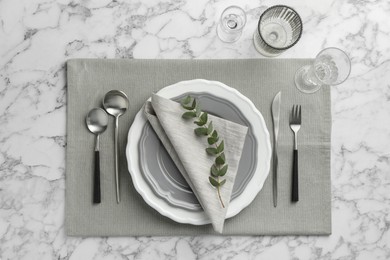 Stylish setting with cutlery, glasses and plates on white marble table, flat lay