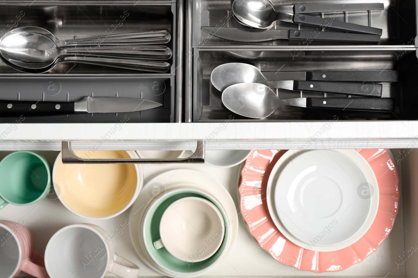 Photo of Ceramic dishware and cutlery in drawers, top view