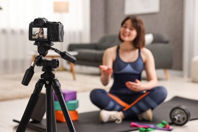 Photo of Happy sports blogger recording fitness lesson at home, focus on camera