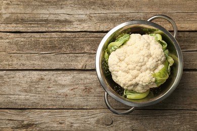 Photo of Metal colander with cauliflower on wooden table, top view. Space for text