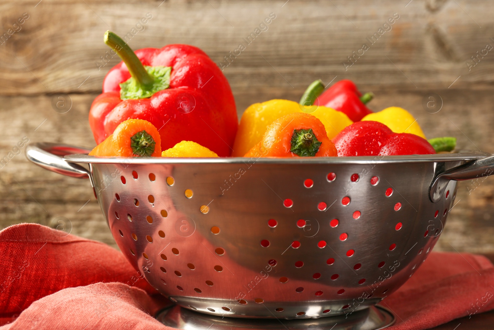 Photo of Metal colander with fresh peppers on table, closeup