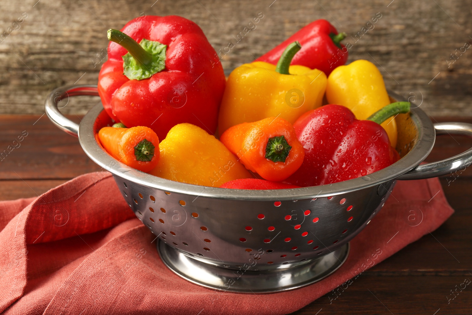 Photo of Metal colander with fresh peppers on table, closeup