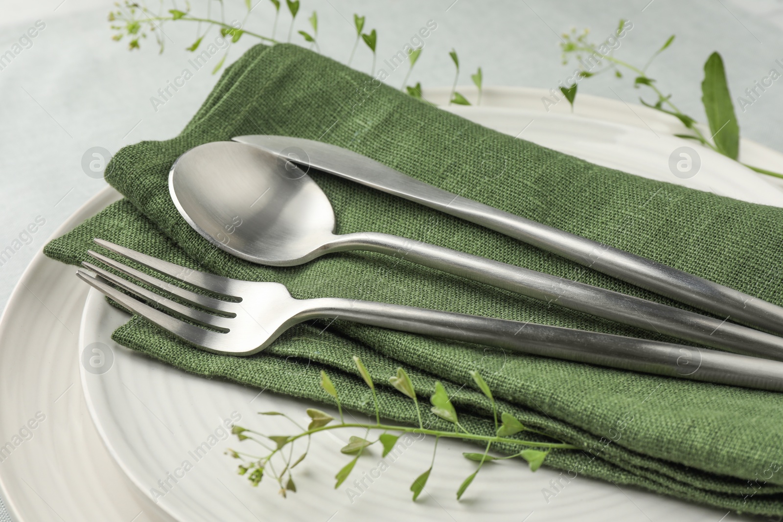 Photo of Stylish setting with cutlery, leaves and plates on table, closeup