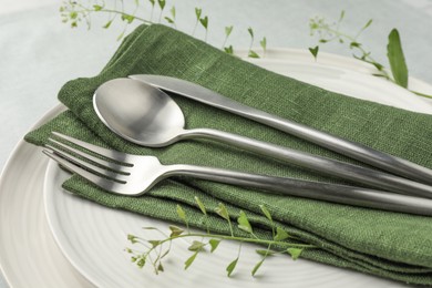 Stylish setting with cutlery, leaves and plates on table, closeup