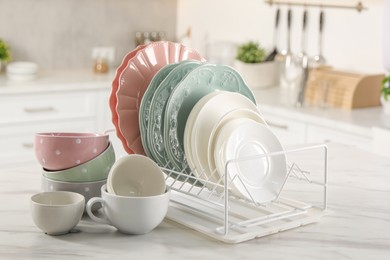 Photo of Many different clean dishware and cups on white marble table in kitchen