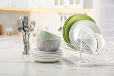Photo of Many different clean dishware, cups and cutlery on white marble table in kitchen