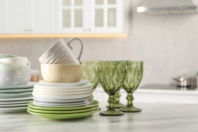 Many different clean dishware, glasses and cup on white marble table indoors. Space for text