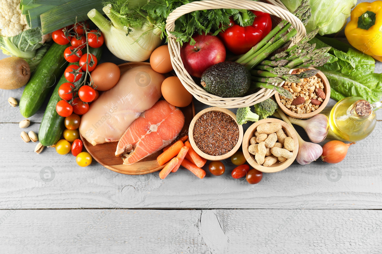 Photo of Healthy food. Basket with different fresh products on grey wooden table, flat lay. Space for text