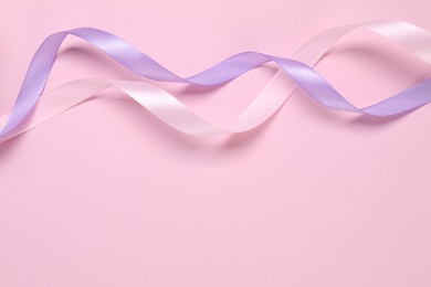 Beautiful ribbons in different colors on pink background, flat lay