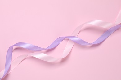 Beautiful ribbons in different colors on pink background, flat lay