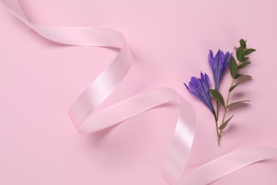 Beautiful ribbon with flowers on pink background, closeup