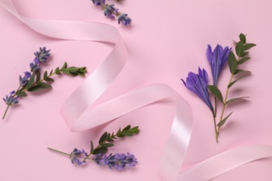 Photo of Beautiful ribbon with flowers on pink background, closeup