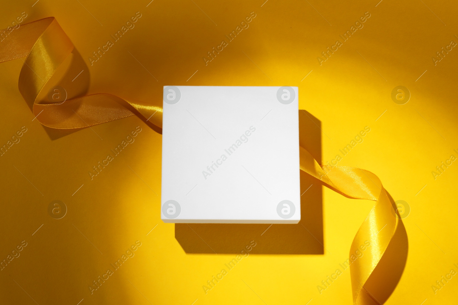 Photo of Beautiful bright ribbon and podium on yellow background, flat lay