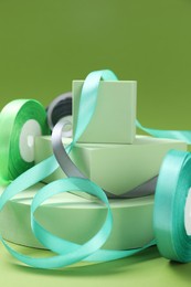 Photo of Beautiful ribbon reels and different podiums on green background, closeup