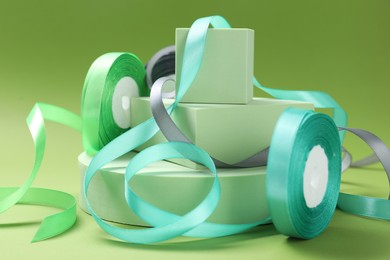 Photo of Beautiful ribbon reels and different podiums on green background, closeup