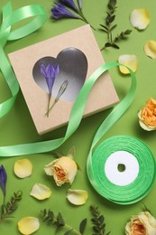 Photo of Flat lay composition with beautiful ribbon reel and gift box on green background