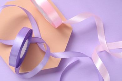 Photo of Beautiful ribbon reels and podium on violet background, flat lay