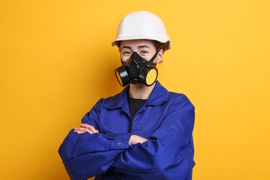 Worker in respirator and helmet on orange background