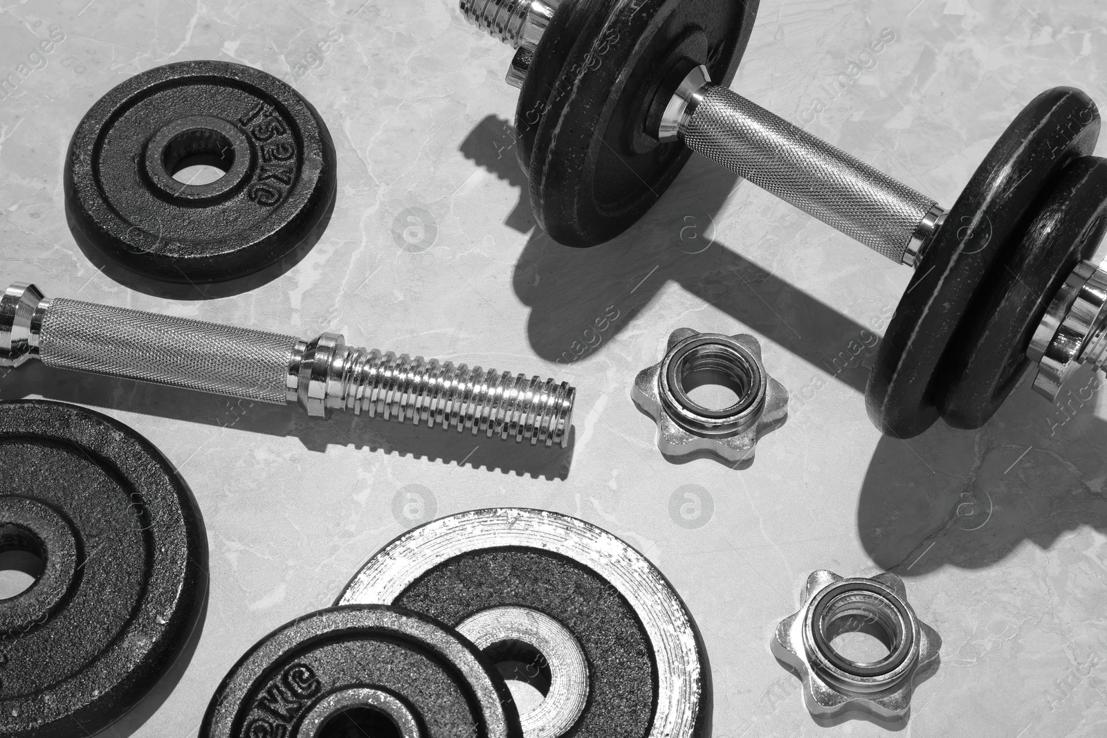 Photo of Barbell and parts of one on grey floor, above view