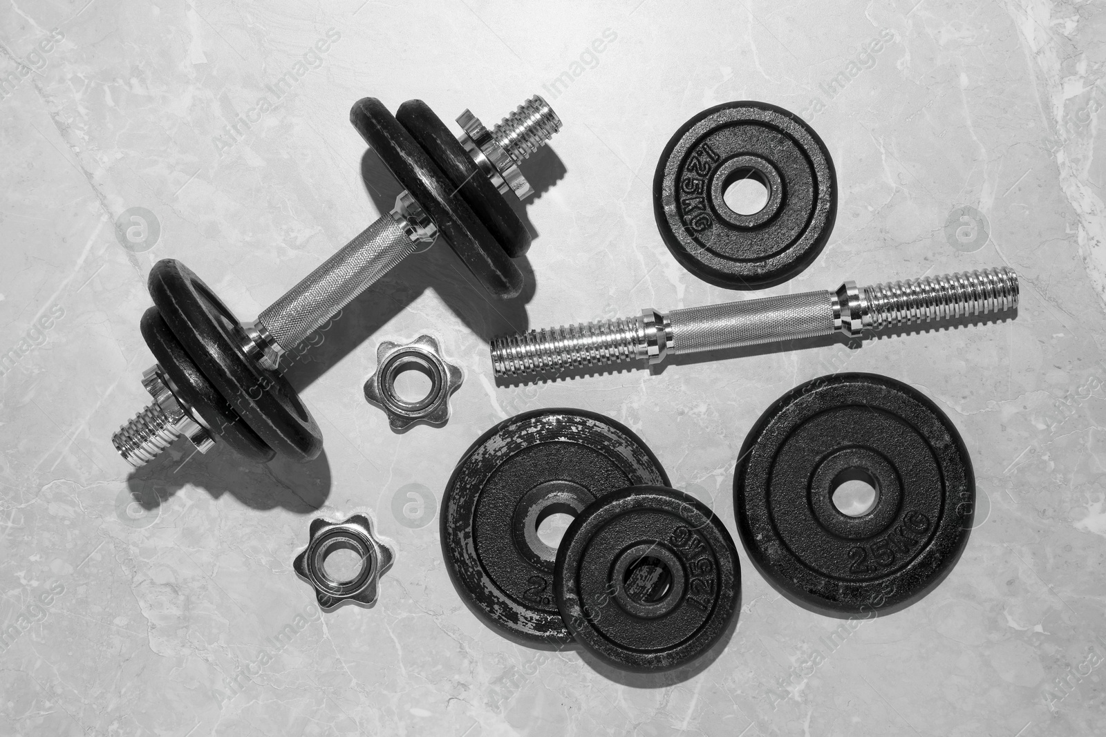 Photo of Barbell and parts of one on grey floor, flat lay