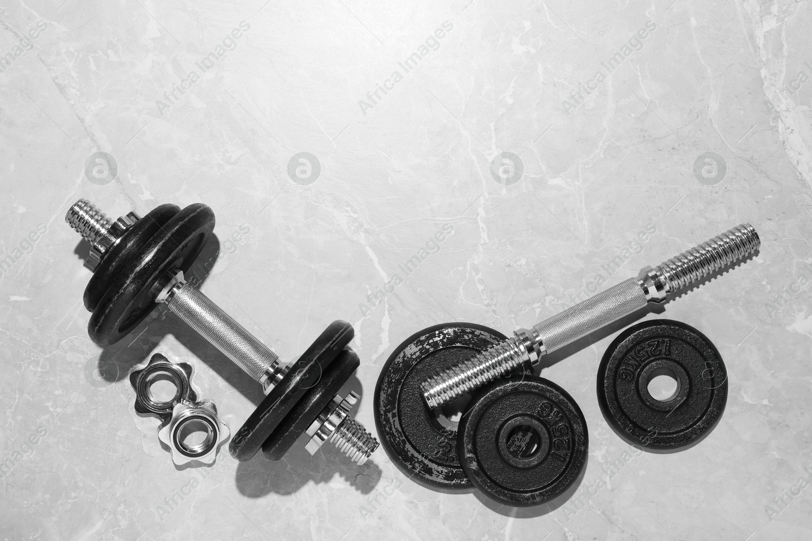 Photo of Barbell and parts of one on grey floor, flat lay. Space for text