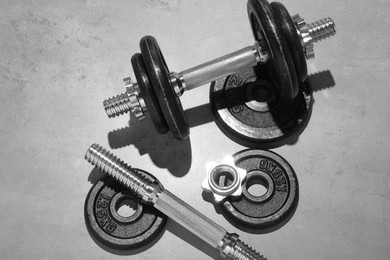 Barbell and parts of one on grey floor, flat lay