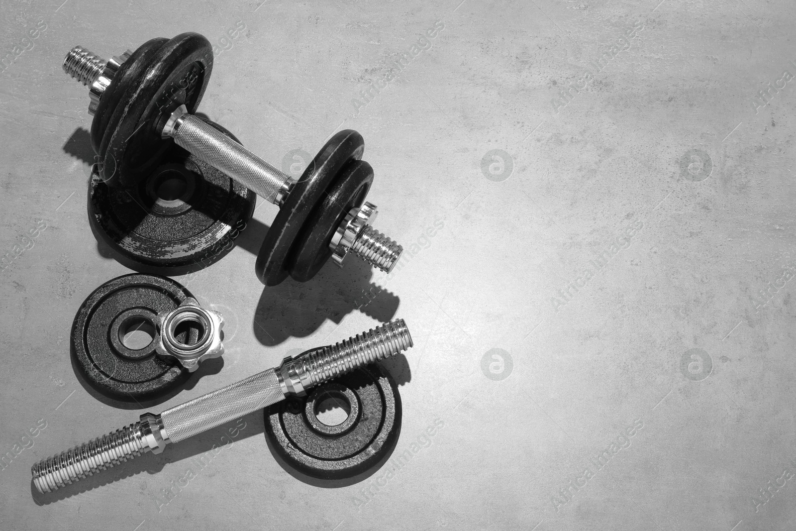 Photo of Barbell and parts of one on grey floor, flat lay. Space for text