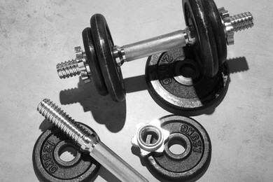 Photo of Barbell and parts of one on grey floor, flat lay