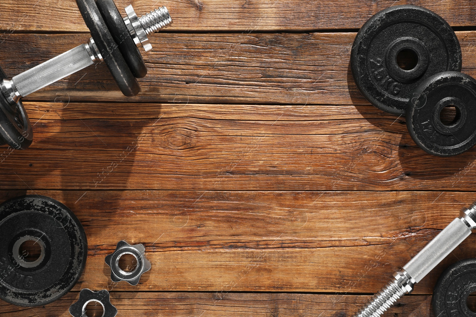 Photo of Barbell and parts of one on wooden floor, flat lay. Space for text