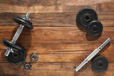 Barbell and parts of one on wooden floor, flat lay. Space for text