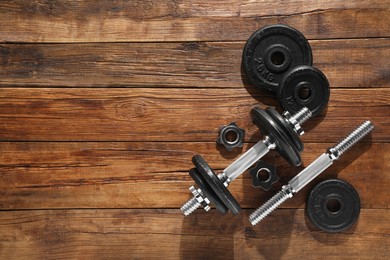 Barbell and parts of one on wooden floor, flat lay. Space for text