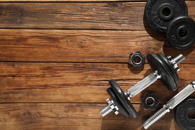 Barbell and parts of one on wooden floor, flat lay. Space for text