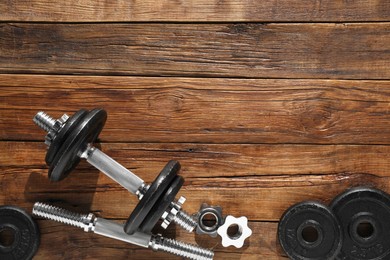 Photo of Barbell and parts of one on wooden floor, flat lay. Space for text