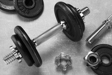 Barbell and parts of one on grey textured background, flat lay