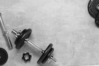 Barbell and parts of one on grey textured background, flat lay. Space for text