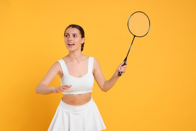 Photo of Young woman with badminton racket on orange background