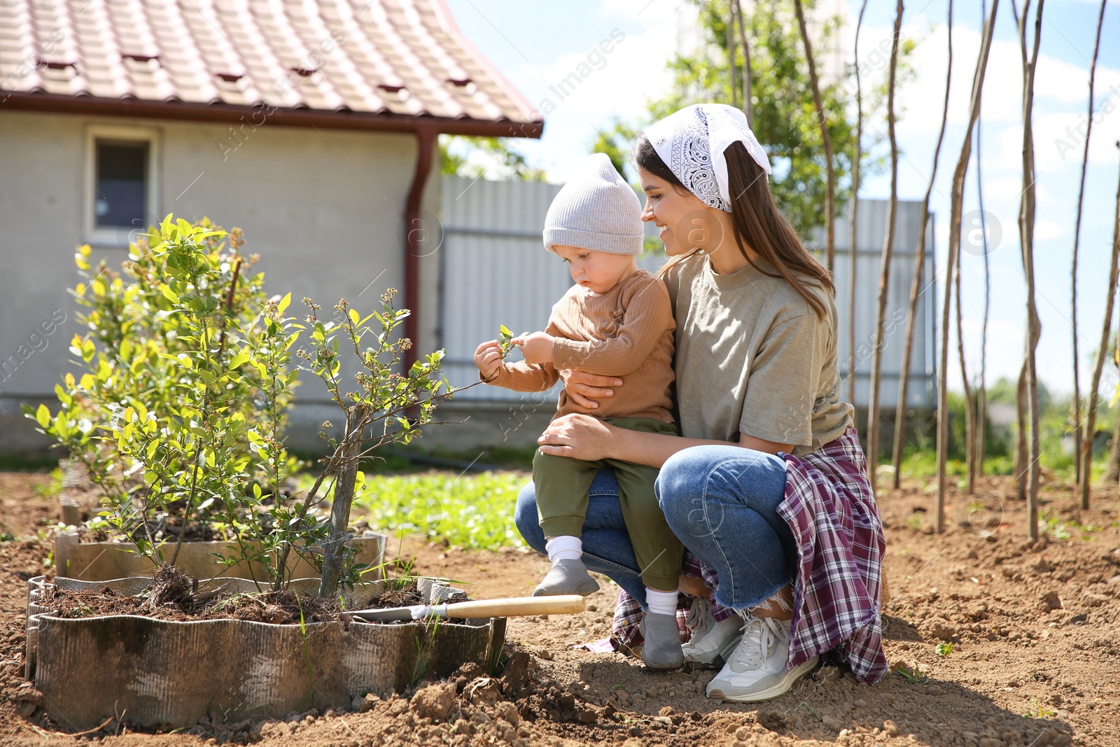 Photo of Mother and her son planting tree together in garden