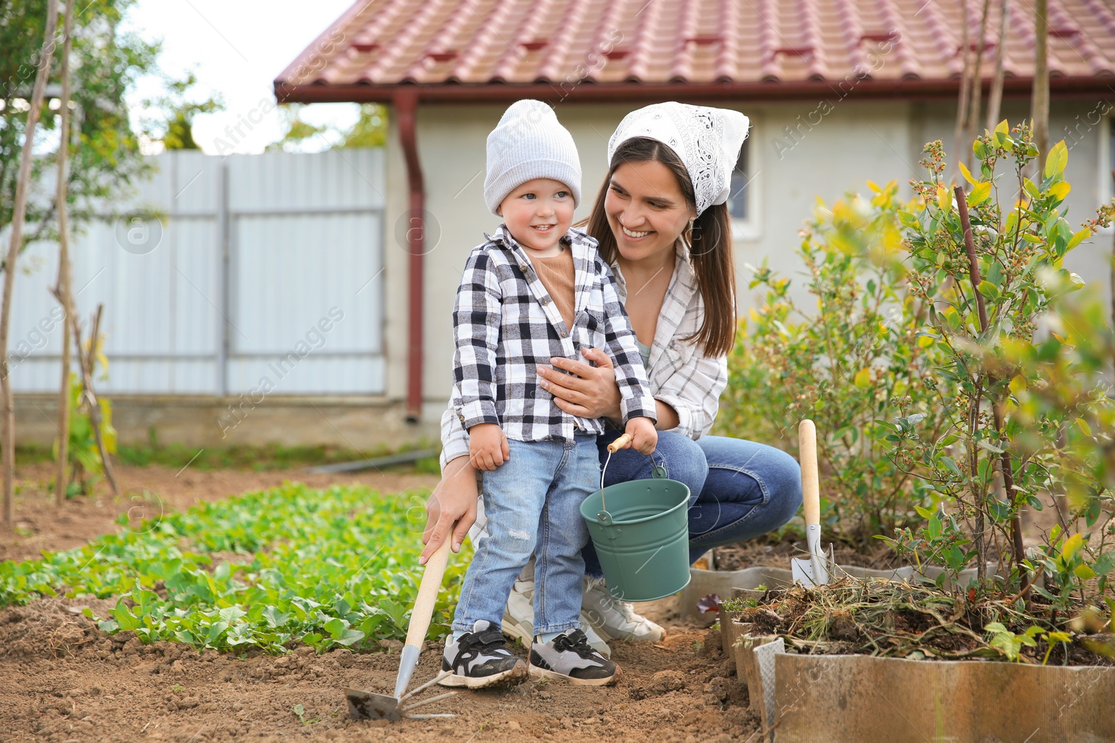 Photo of Mother and her cute son planting tree together in garden