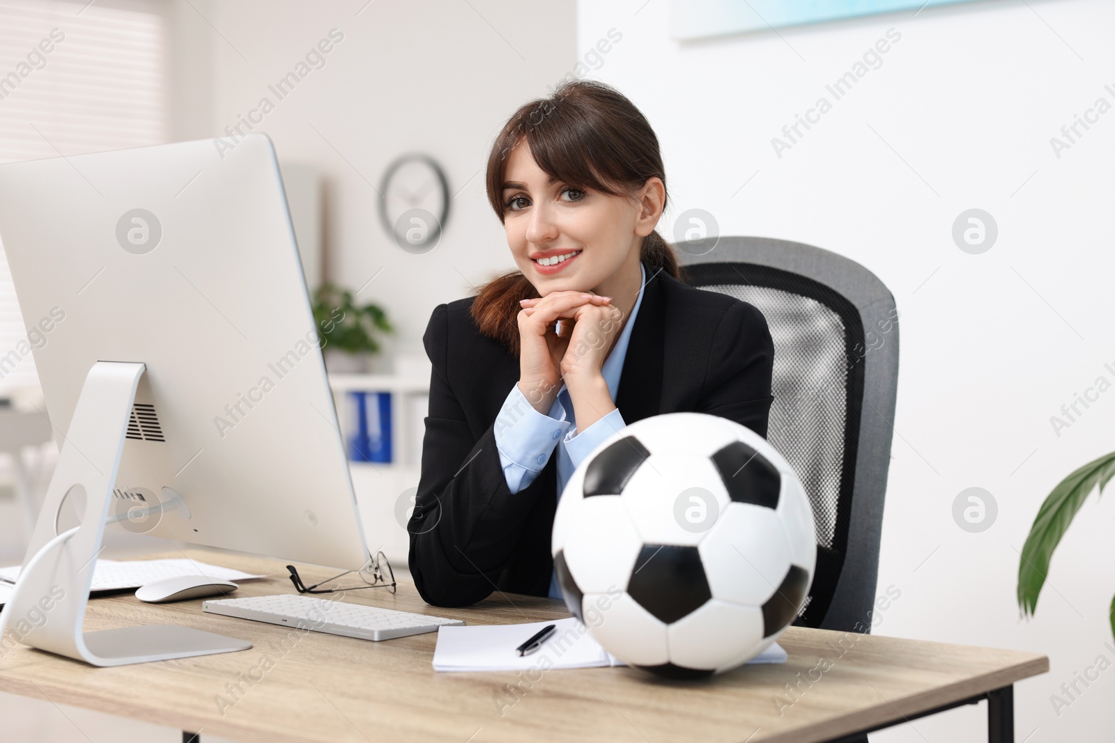 Photo of Smiling employee with soccer ball at table in office