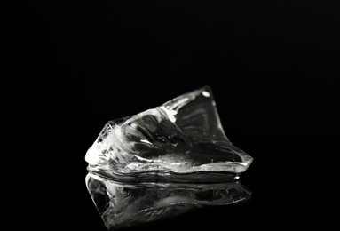 Piece of clear ice on black mirror surface