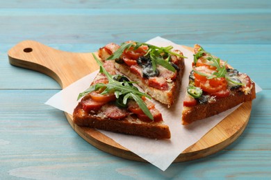 Photo of Tasty pizza toasts on light blue wooden table