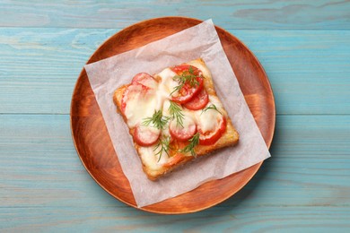 Tasty pizza toast with cheese, tomato and dill on light blue wooden table, top view