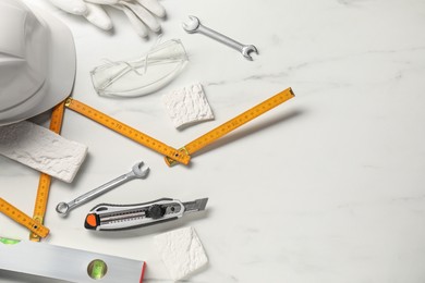 Photo of Flat lay composition with building level and other different construction tools on white marble background, space for text