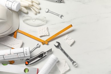 Photo of Flat lay composition with building level and other different construction tools on white marble background, space for text