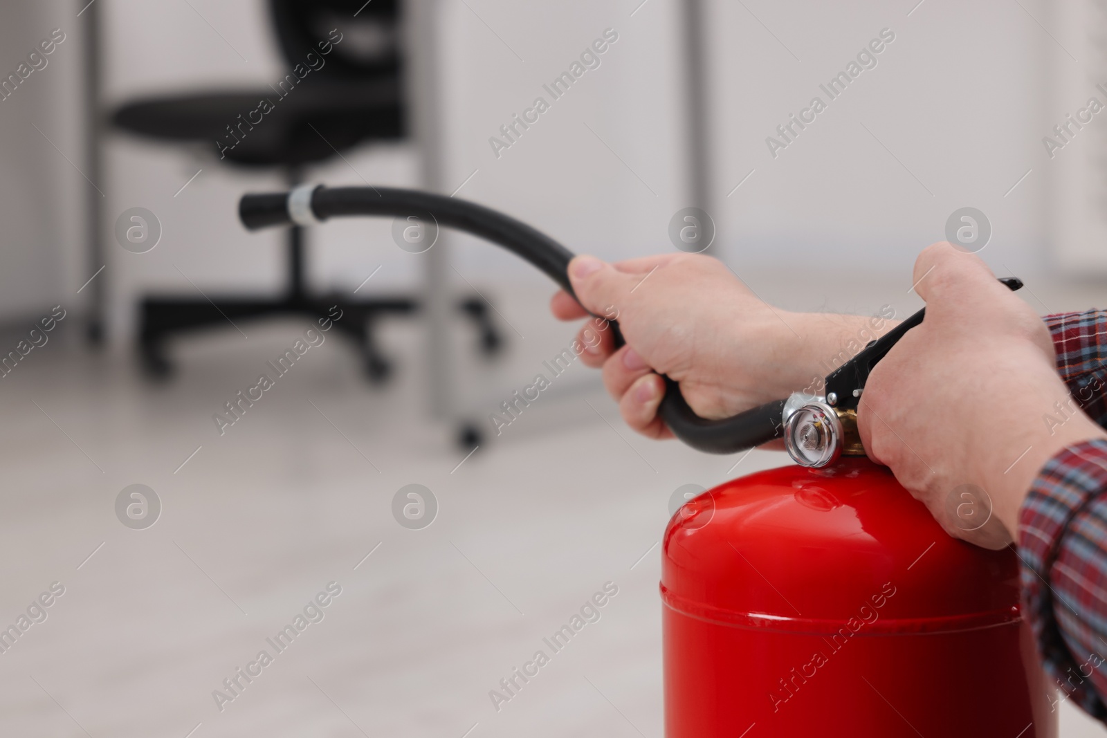 Photo of Man with one fire extinguisher indoors, closeup